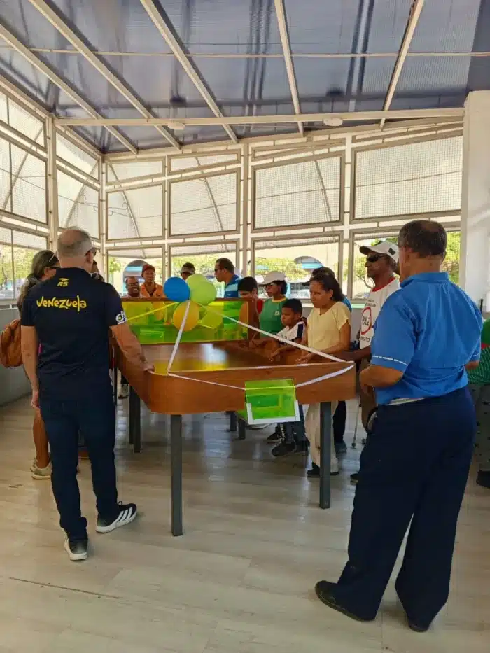Mesa de Showdown adornada para su inauguración, rodeada por Wilmer Gómez y demás asistentes al acto.